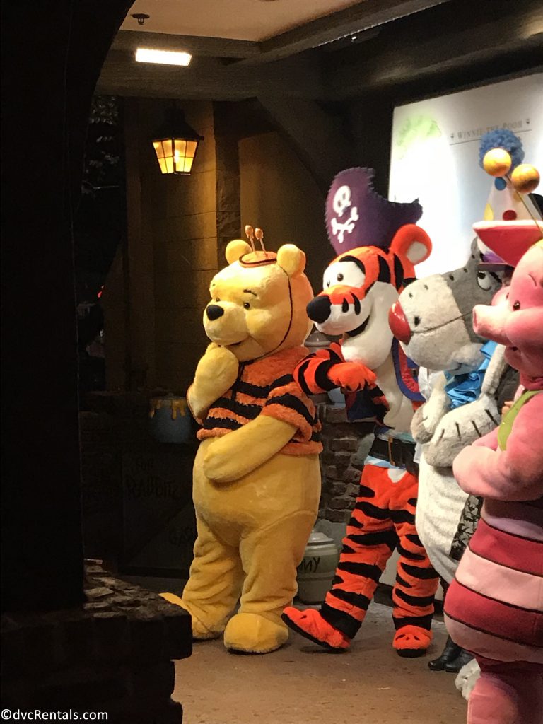Winnie and Pooh, Tigger, Piglet, and Eeyore dressed up in Halloween costumes