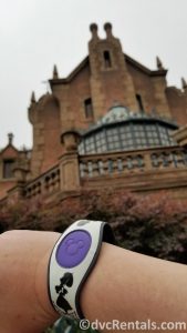 Haunted Mansion Themed Magic Band in front of the Magic Kingdom’s Haunted Mansion