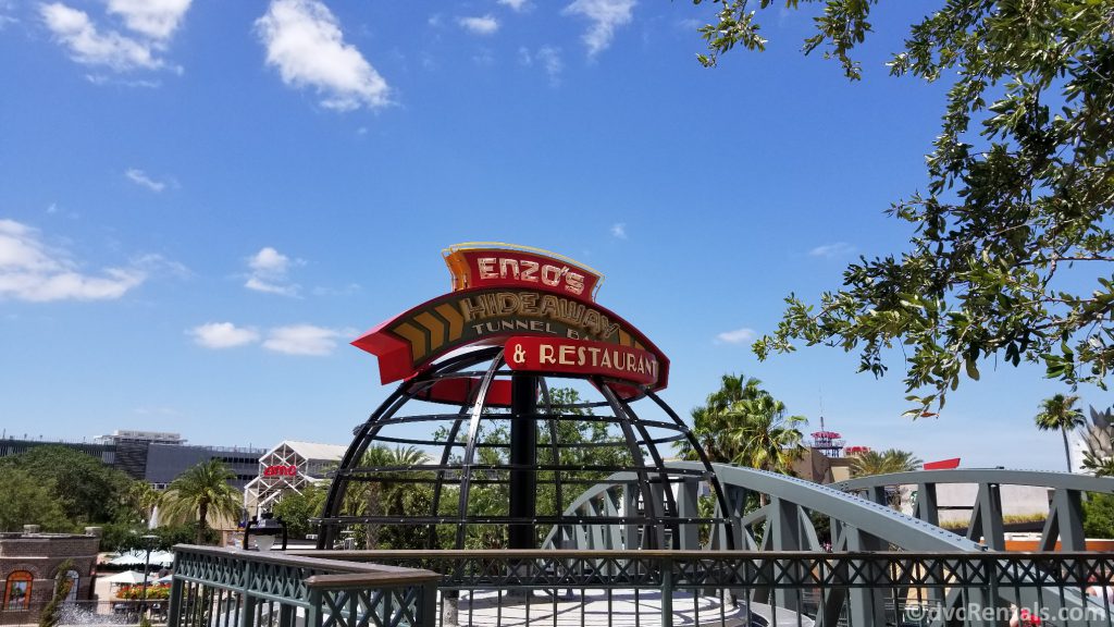 Sign for Enzo’s Hideaway with the AMC Theatre in the background