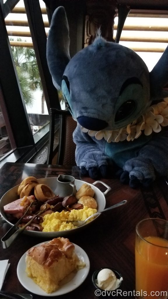 Stitch visiting a table at ‘Ohana restaurant at Disney’s Polynesian Villas and Bungalows