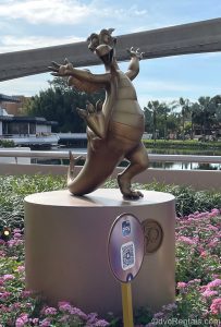 A gold 50th Anniversary statue at EPCOT depicting Figment.