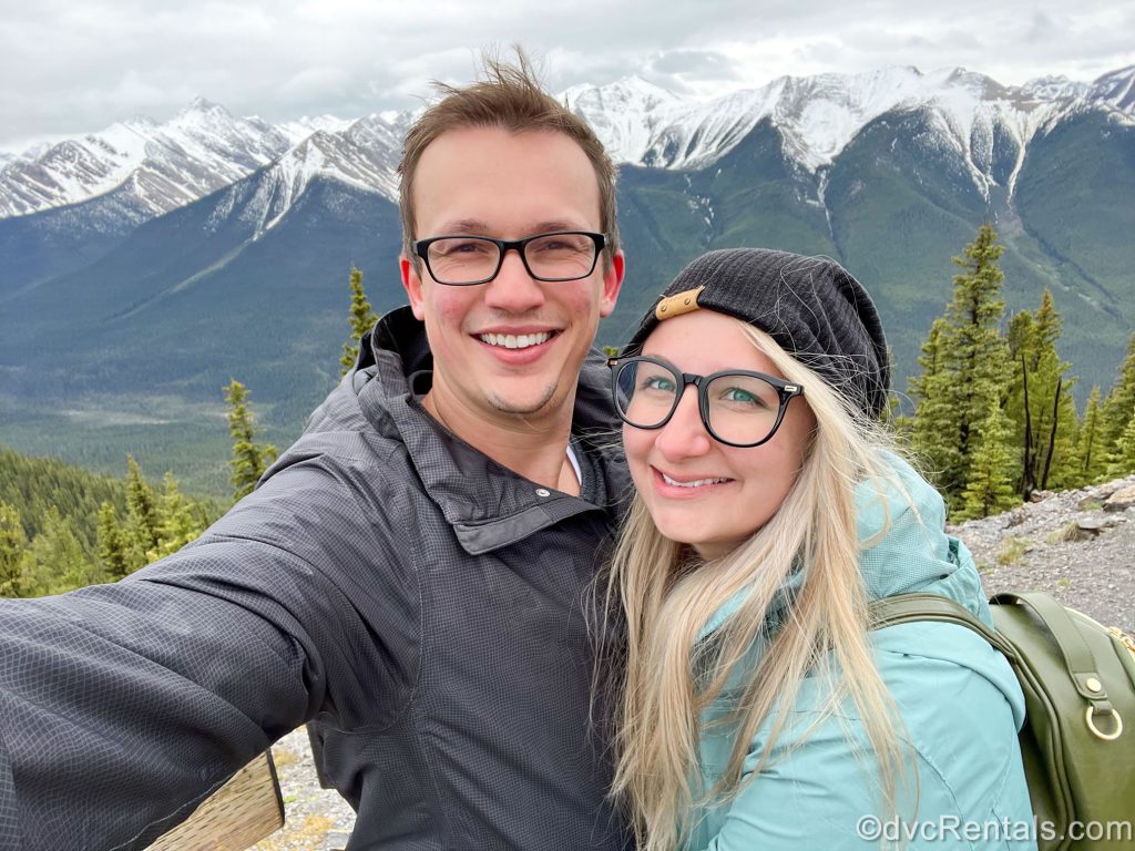A photo of Cassie and her husband in front of a mountain range