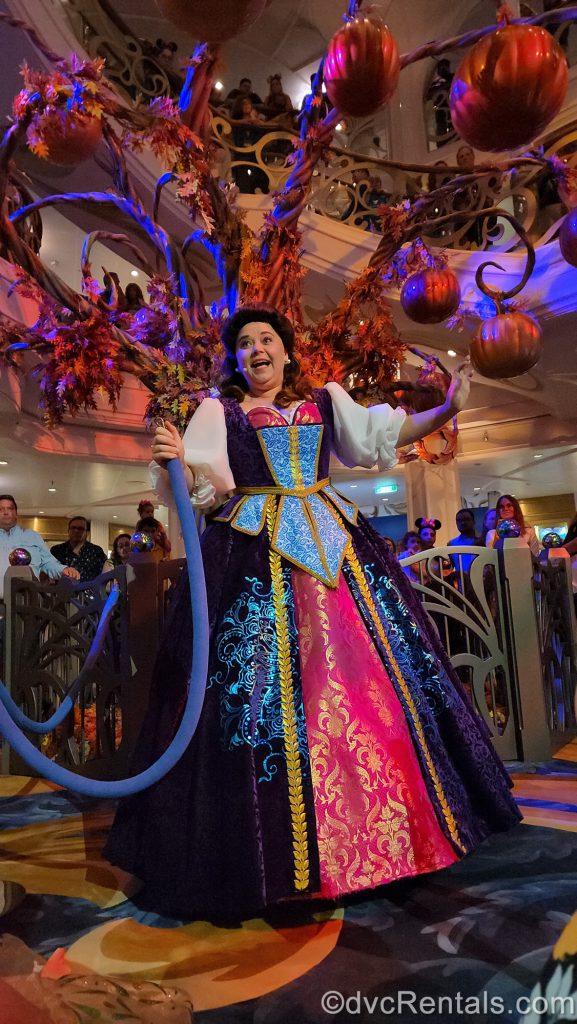 A photo of a Cast Member in front of the Pumpkin Tree in the Grand Hall