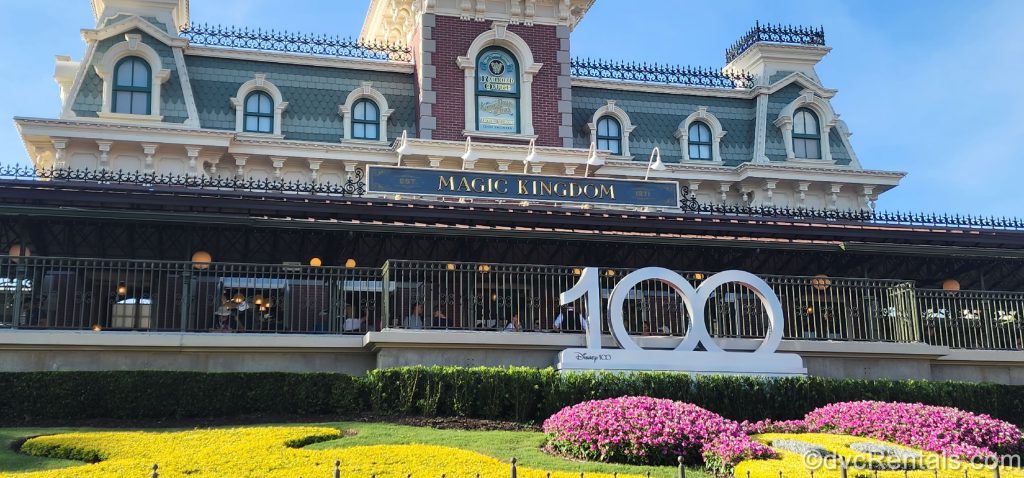 Magic Kingdom Railroad Office with large 100th Anniversary sign in front. The large sign sits within a flower bed.