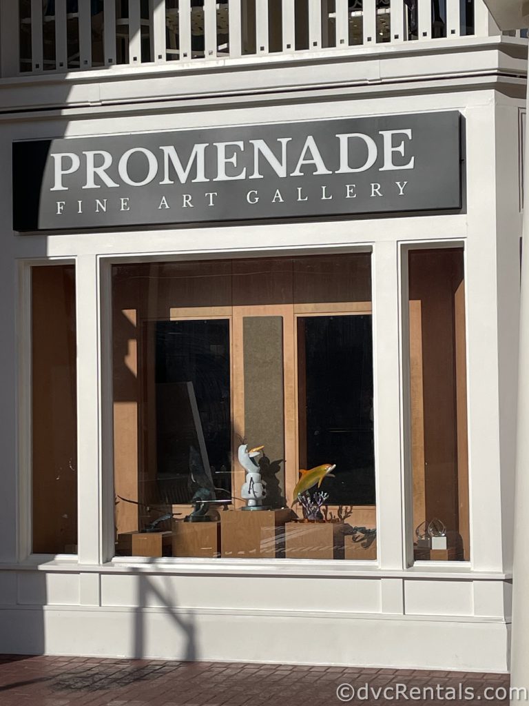 Storefront with black and white awning and white framing around the windows and door. A black sign has white writing that reads “Promenade Fine Art Gallery.”