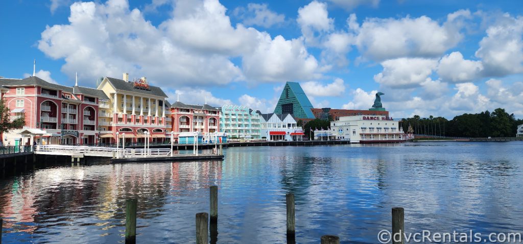 The colorful building of Disney Boardwalk, with the boat dock and the waters of Crescent Lake. The Boardwalk is reflected in the water.