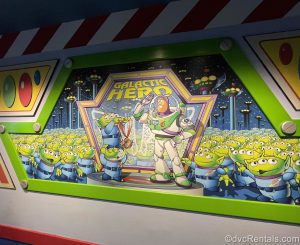 Galatic Hero Mural at the end of the ride. Buzz Lightyear is standing next to the words “Galactic Hero” and surrounded by aliens.