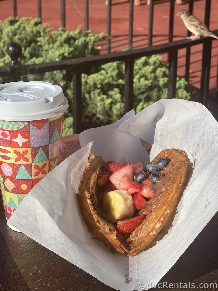 Walt Disney World Coffee Cup sitting next to a Waffle filled with Nutella and fruit.