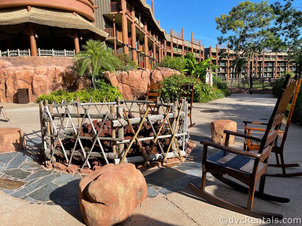 Wooden chairs around a fire pit in front of the resort.