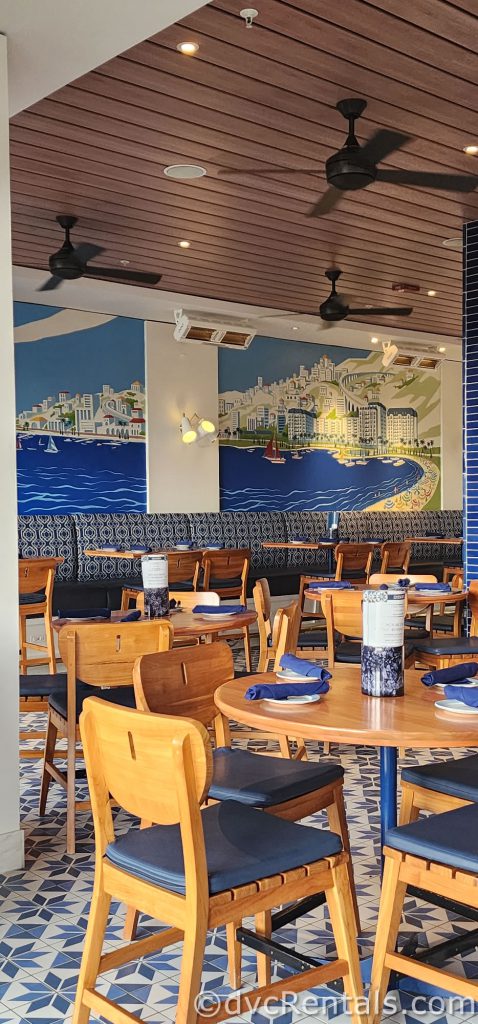 Inside Bar Riva. There is a mural of a European beach painted on the wall, and the decor is all wood and bright blue.