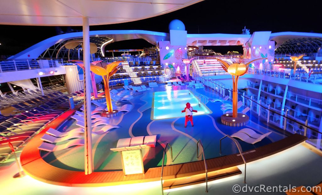 Main Pool Deck onboard the Wonder of the Seas at night. A Lifeguard is standing on duty.