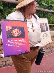 Cast Member holding a Sign showcasing the party-exclusive Sweet Potato Fries.