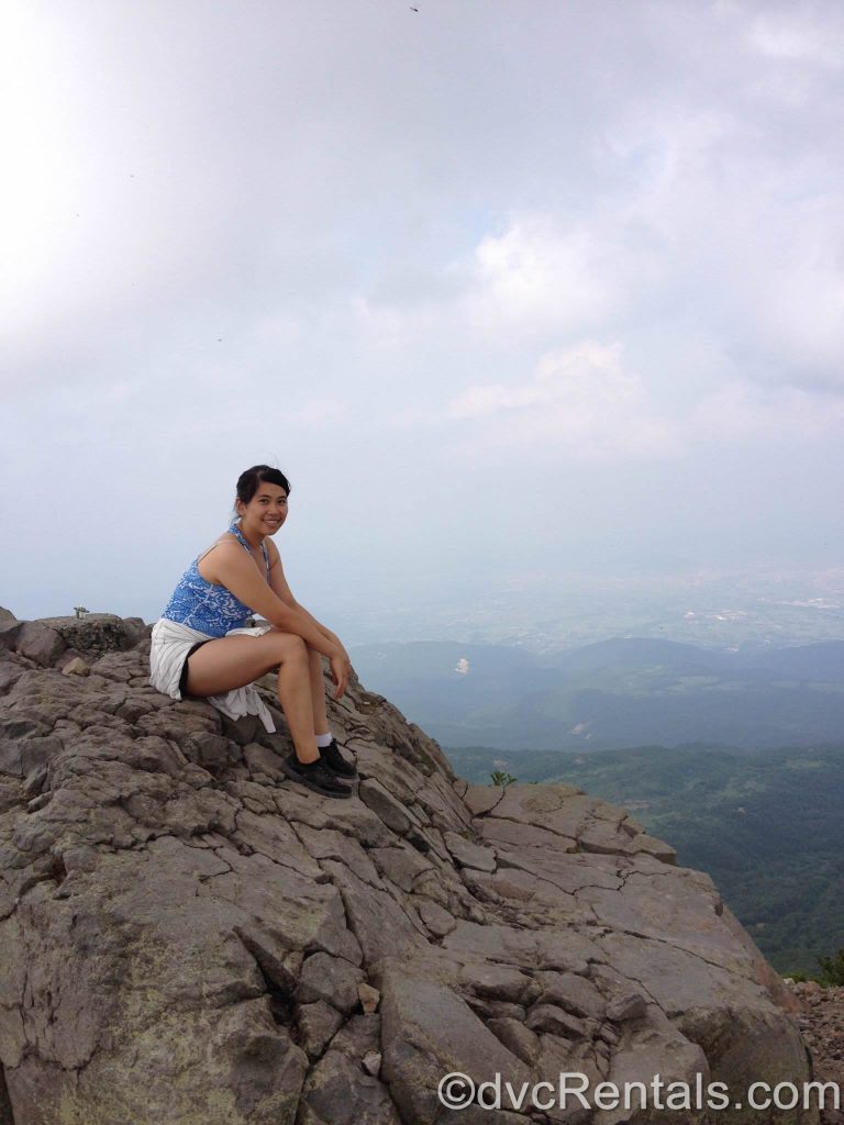 Joanne sitting at the top of a mountain.