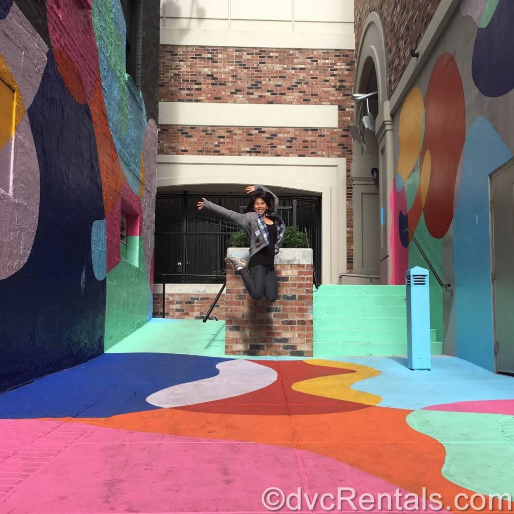 Joanne jumping in the air in a colorfully painted alley.