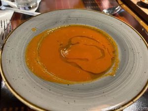Sanaa Tomato Soup in a light blue bowl drizzled with oil.