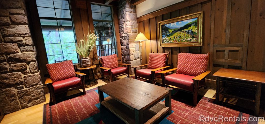 Seating area in the Carolwood Pacific Room at Boulder Ridge Villas. Red chairs sit around a wooden table.