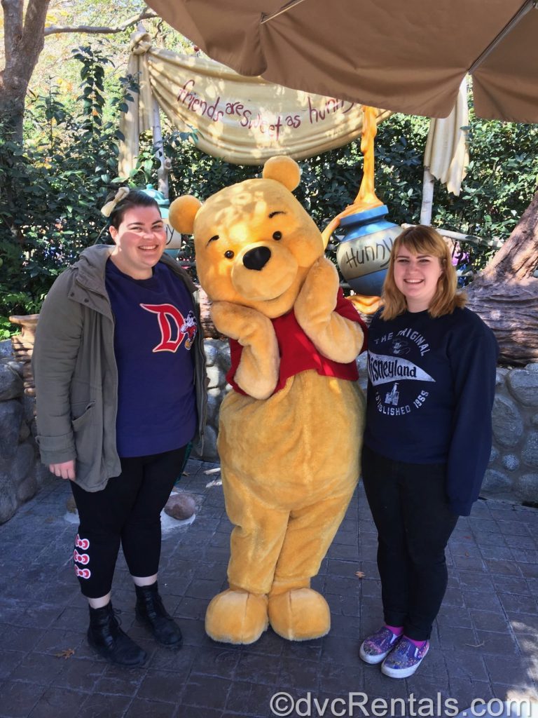 Emma and her sister posing with Winnie the Pooh.