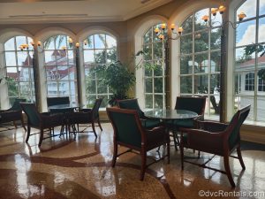 Dark green tables with wood chairs sitting in front of floor-to-ceiling glass windows at Citricos.