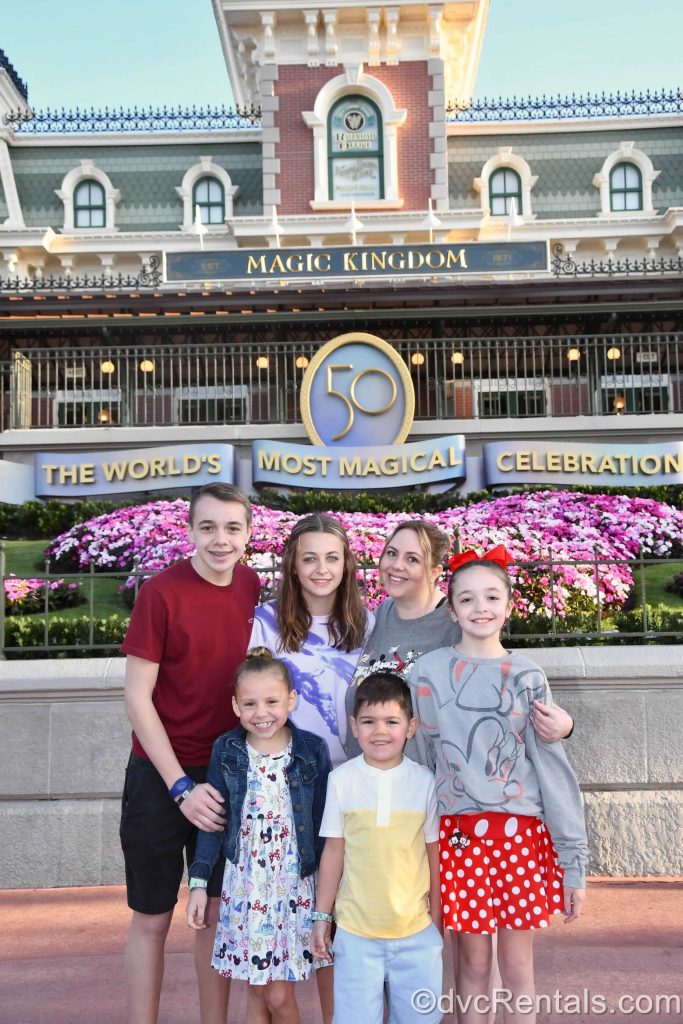 Stacy posing with her three nieces and two nephews at the entrance to Magic Kingdom.