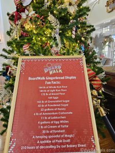 Sign about the Gingerbread Boardwalk Deli with a Christmas Tree in the Background.