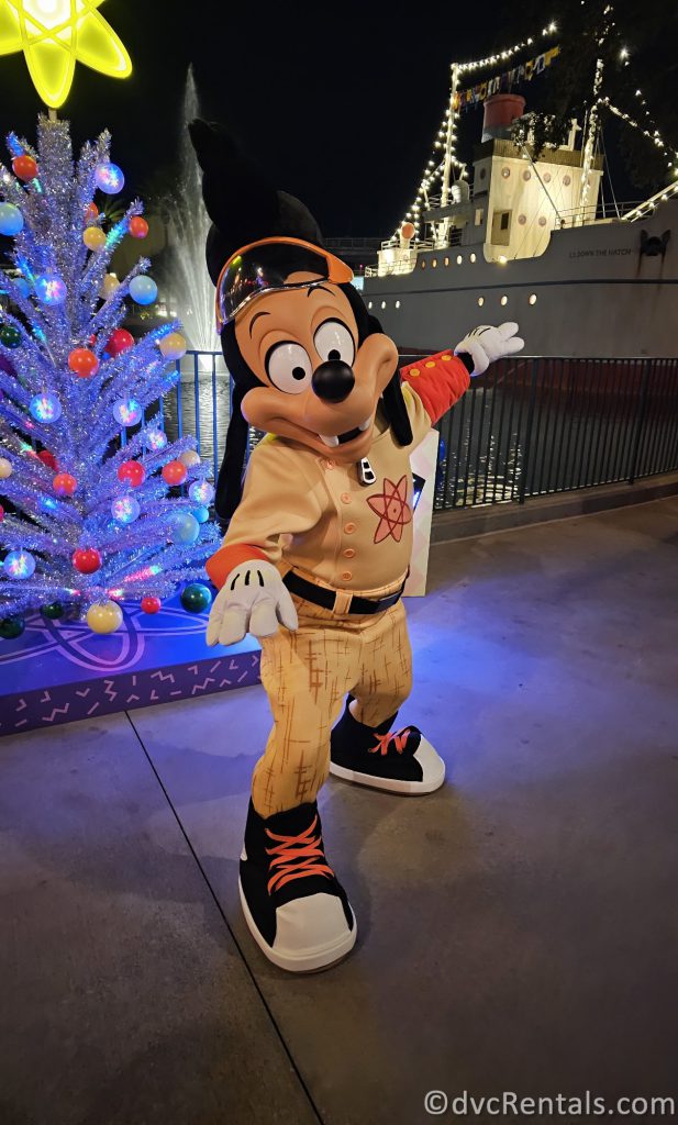 Max dressed as Powerline posing in front of a White Christmas Tree.