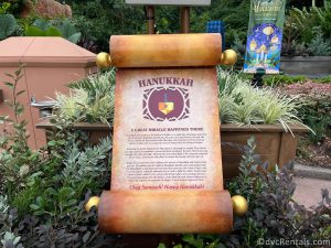 Scroll sharing the Hanukkah traditions sitting in front of a garden.