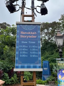 Blue Hanukkah Storyteller Sign outlining story times hanging from a lamppost.