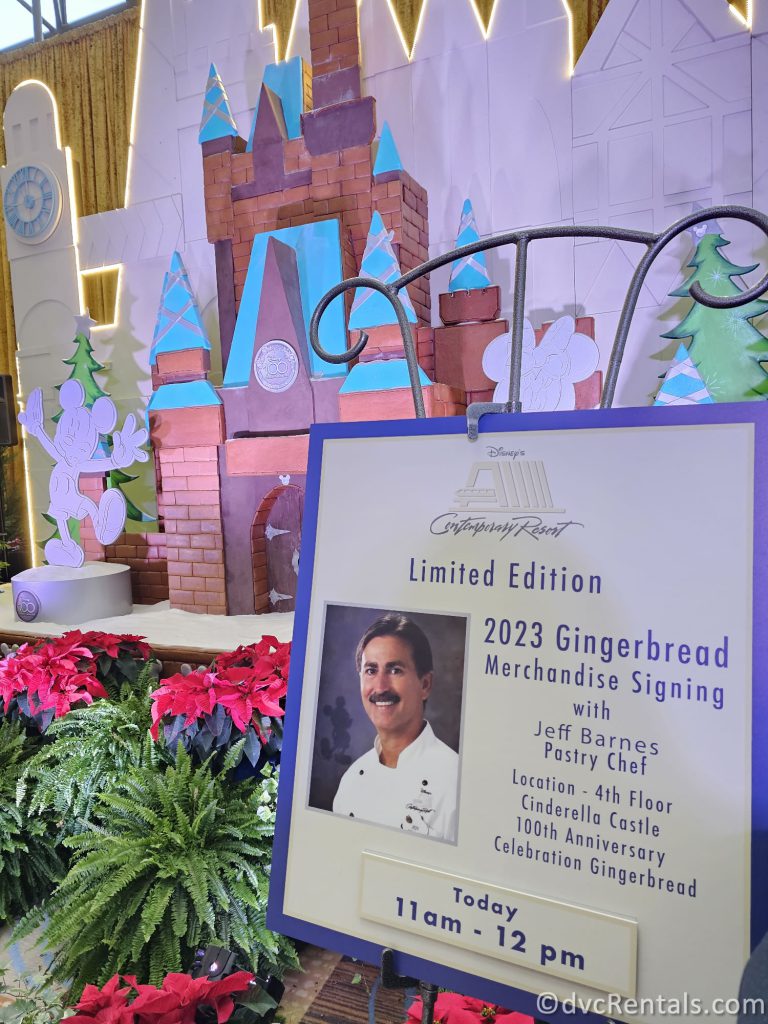 Poster of the Chef who created the Gingerbread Castle with the Gingerbread Castle in the background.