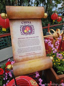 Scroll sharing the Chinese holiday traditions sitting amongst flowers and red lanterns.
