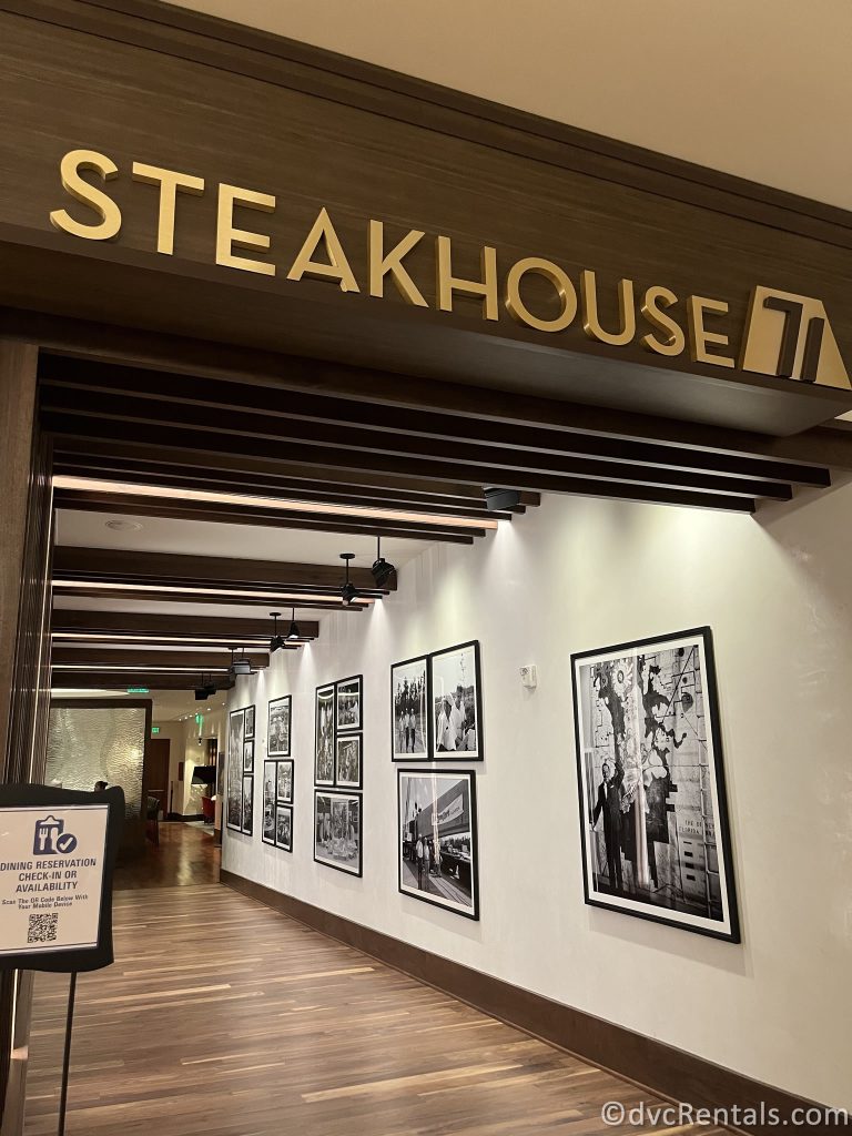 Exterior of Steakhouse 71. The sign is wooden with gold lettering, and black and white photos are on the wall down the hallway.