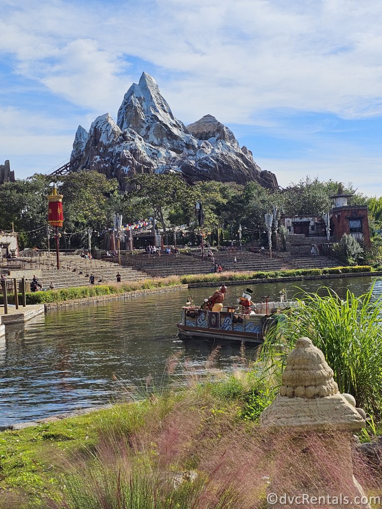 Lake in Disney's Animal Kingdom Park with the Expedition Everest Mountain in the background. Scrooge McDuck stands on a Boat as it sails on the Lake.