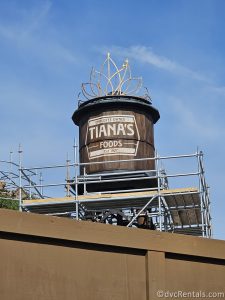 Wooden Water Tower that reads "Tiana's Foods" with a Silver Tiara on top and scaffolding around.
