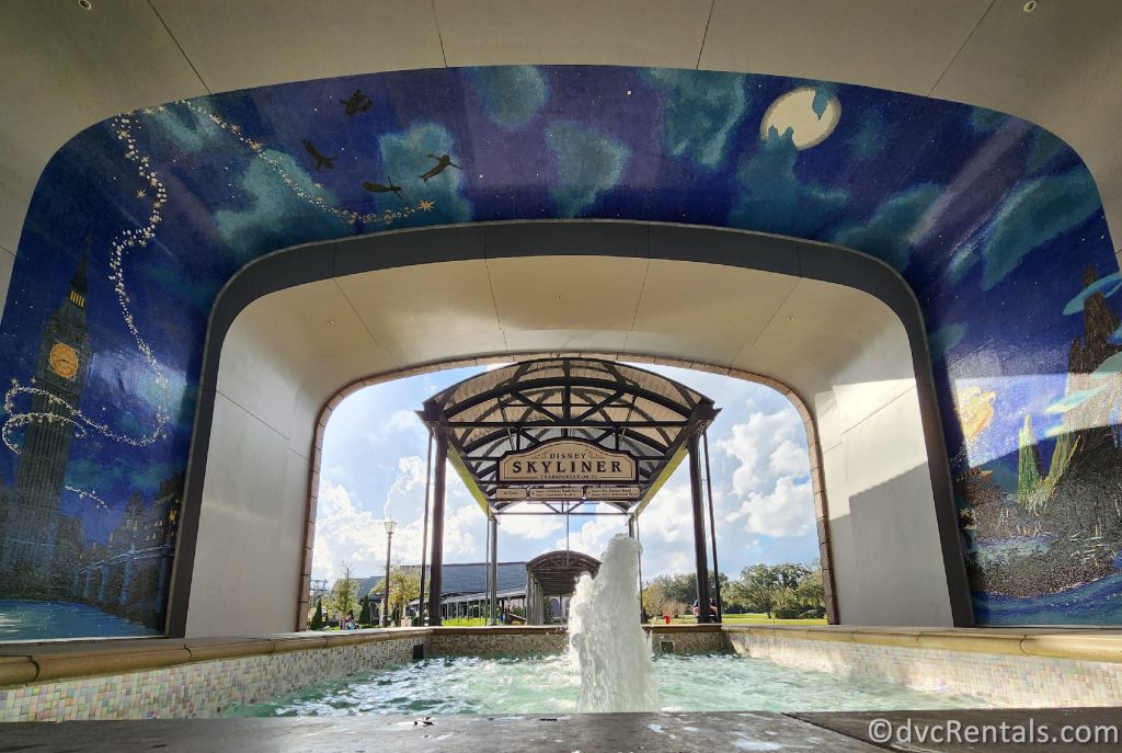Fountain in the walkway with the Peter Pan Mural and the Skyliner in the background.