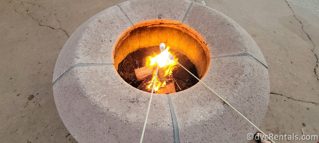 Stone Fire pit with two marshmallows roasting overtop of the fire.