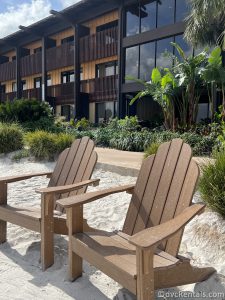 Two Wooden Chairs sitting in the sand in front of one of the buildings at Disney's Polynesian Villas.
