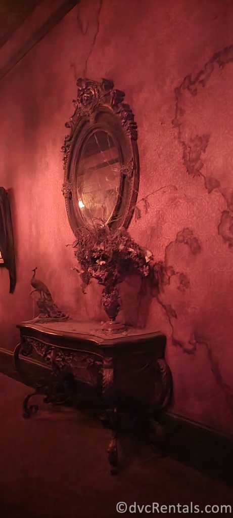 Dusty end table, flower arrangement, and mirror in the Haunted Mansion.