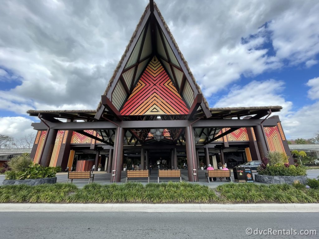 Entrance to Disney's Polynesian Village Resort Great Ceremonial House. The dark wood building has high peaks and red and orange side detailing.