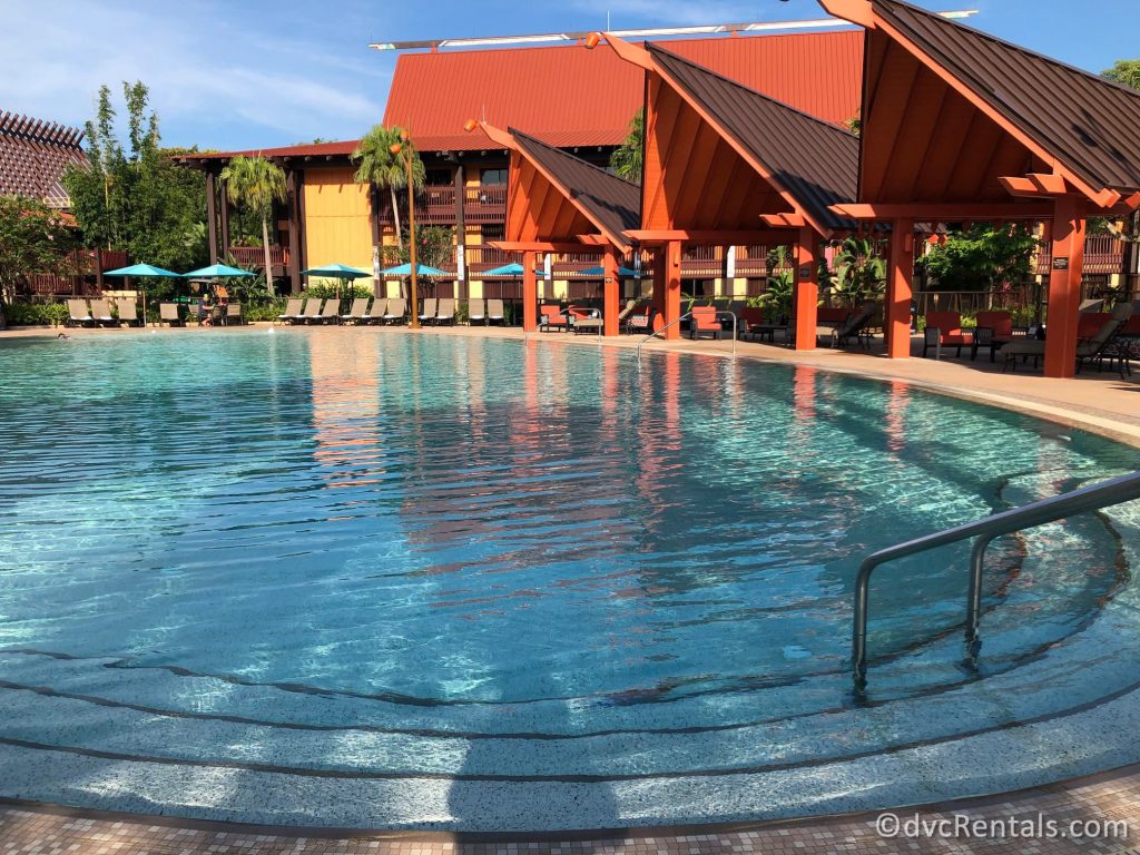 Another angle of the Oasis Pool at Disney's Polynesian Village Resort. There are three orange-roofed cabanas next to the pool.