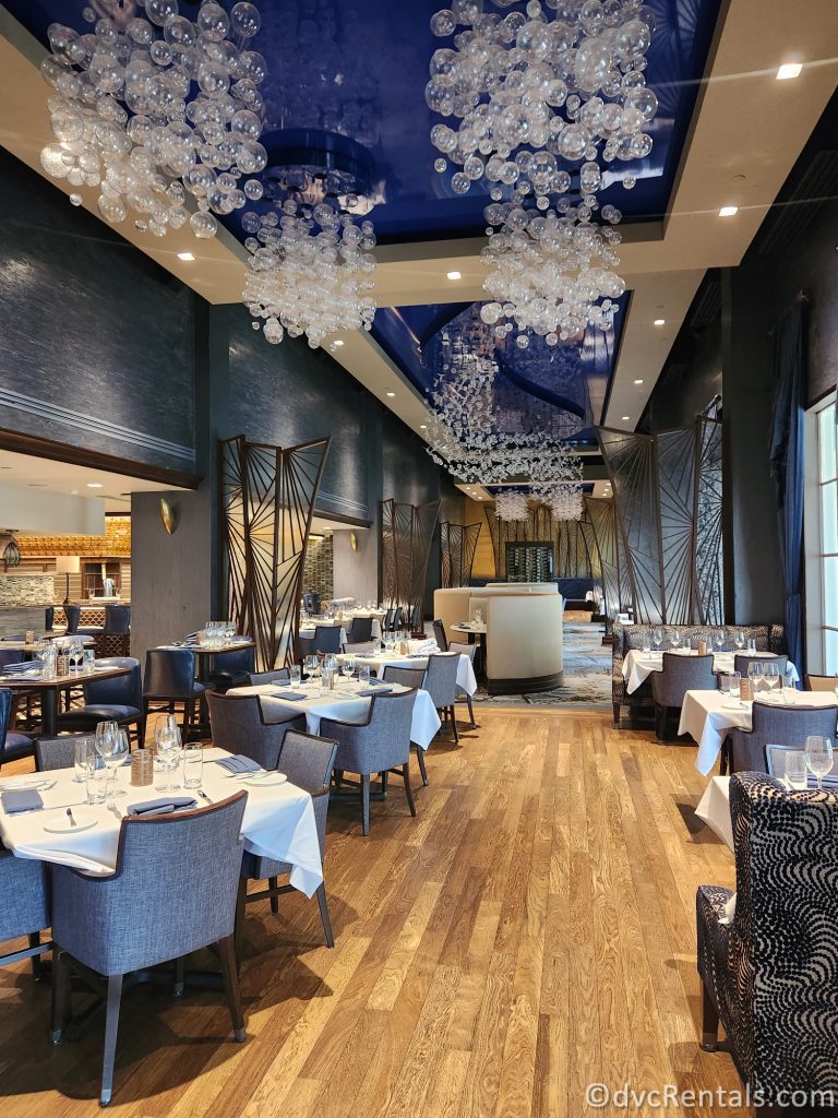 Interior of Flying Fish. Light blue and white tables and chairs sit beneath chandeliers shaped like bubbles.