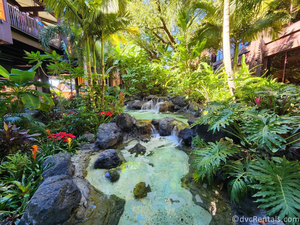 Water running over rocks, surrounded by tropical flowers at the entrance of Disney's Polynesian Village Resort.