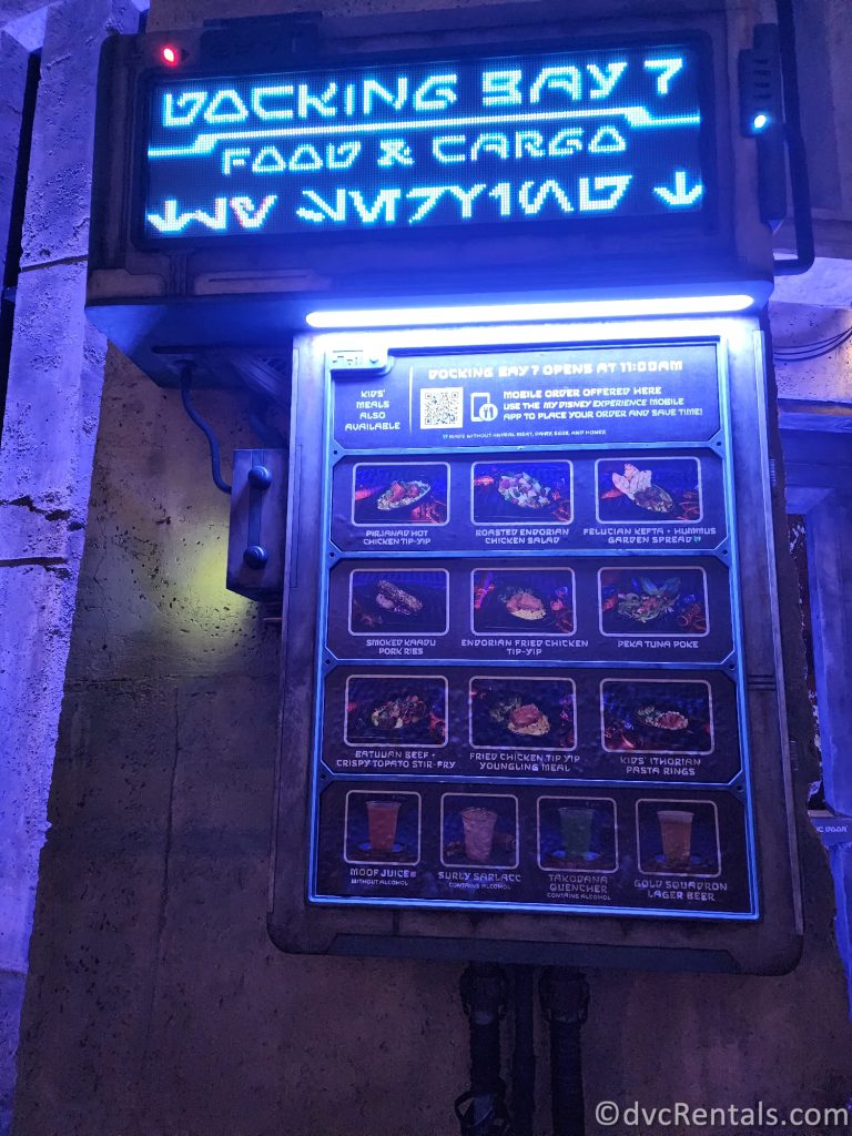 Docking Bay 7 Food and Cargo menu board lit up at night in blue neon.