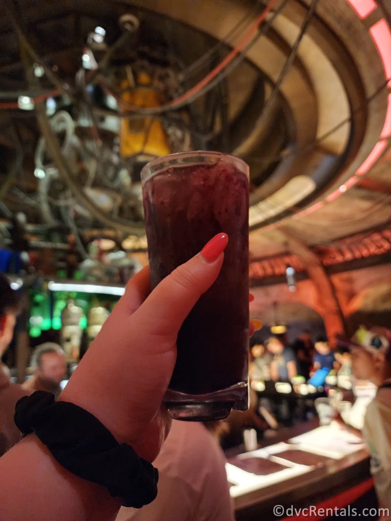 Dark purple drink being held up in Oga's Cantina.