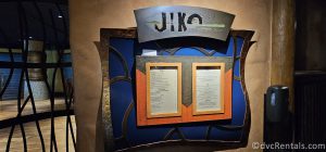 Entrance to Jiko. The name of the restaurant hangs above a dark blue and orange menu board.