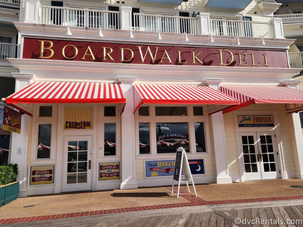 Exterior of the Boardwalk Deli. Gold letters spell out Boardwalk Deli on a large white building.