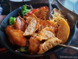 Dumplings, Chicken Wings, Noodles, and Stir Fried Vegetables in a cast iron skillet.