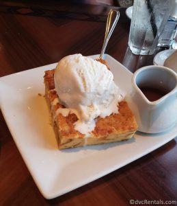 Bread Pudding with Vanilla Ice Cream sitting next to a small container holding caramel sauce.