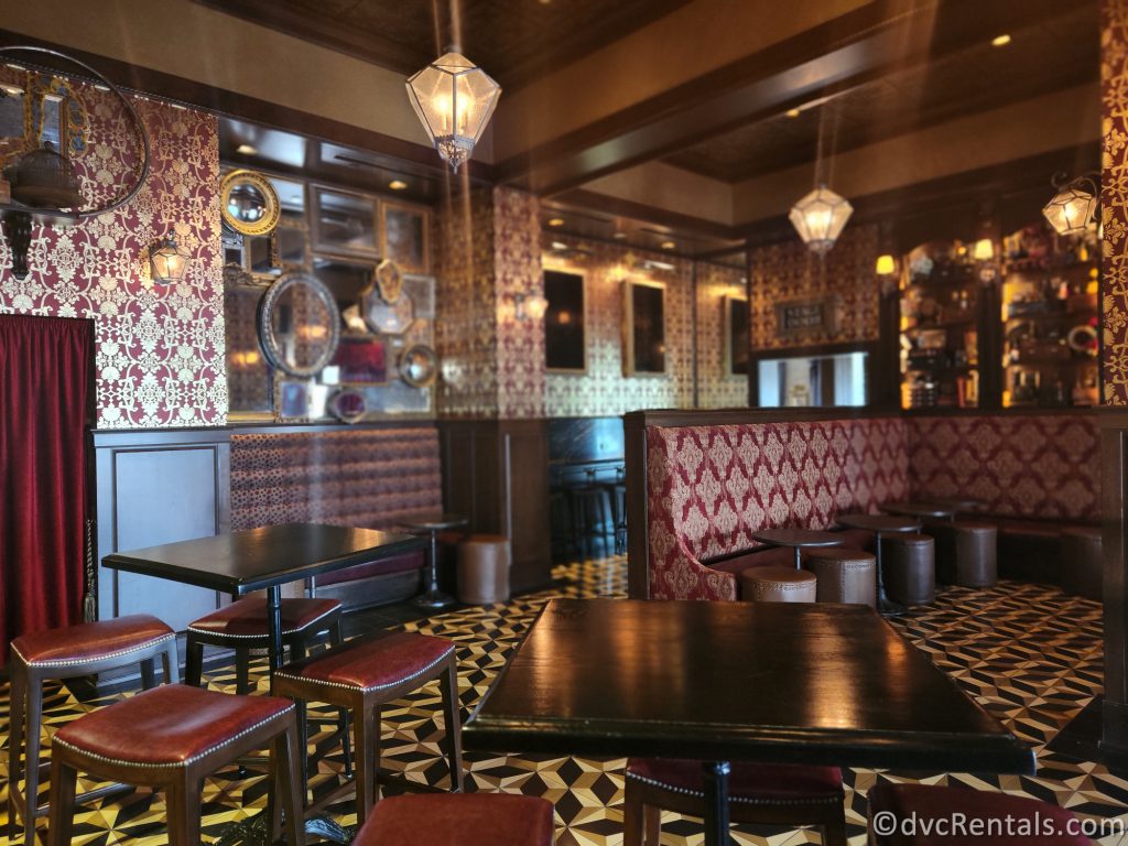 Interior of Abracadabar. Dark wood tables are surrounded by ornate dark red booths and leather chairs.