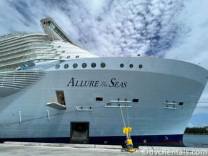 Allure of the Seas cruise ship docked in Nassau. There are bright blue skies above the ship with fluffy white clouds.