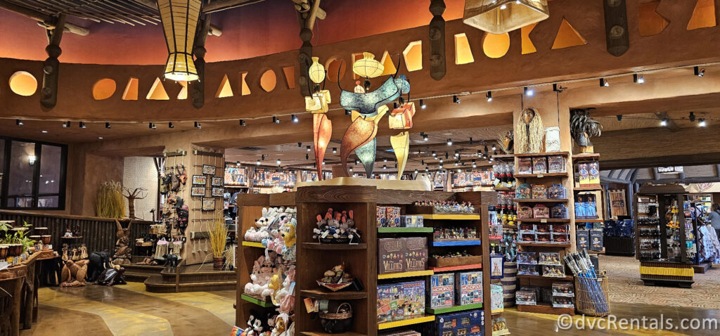 Merchandise in the Resort Gift Shop at Disney's Animal Kingdom Villas. There are multiple displays throughout the shop with dark wood and light sculptures on top of the displays.