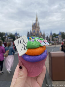 Unbirthday Cupcake from the Cheshire Café being held up in front of Cinderella Castle.
